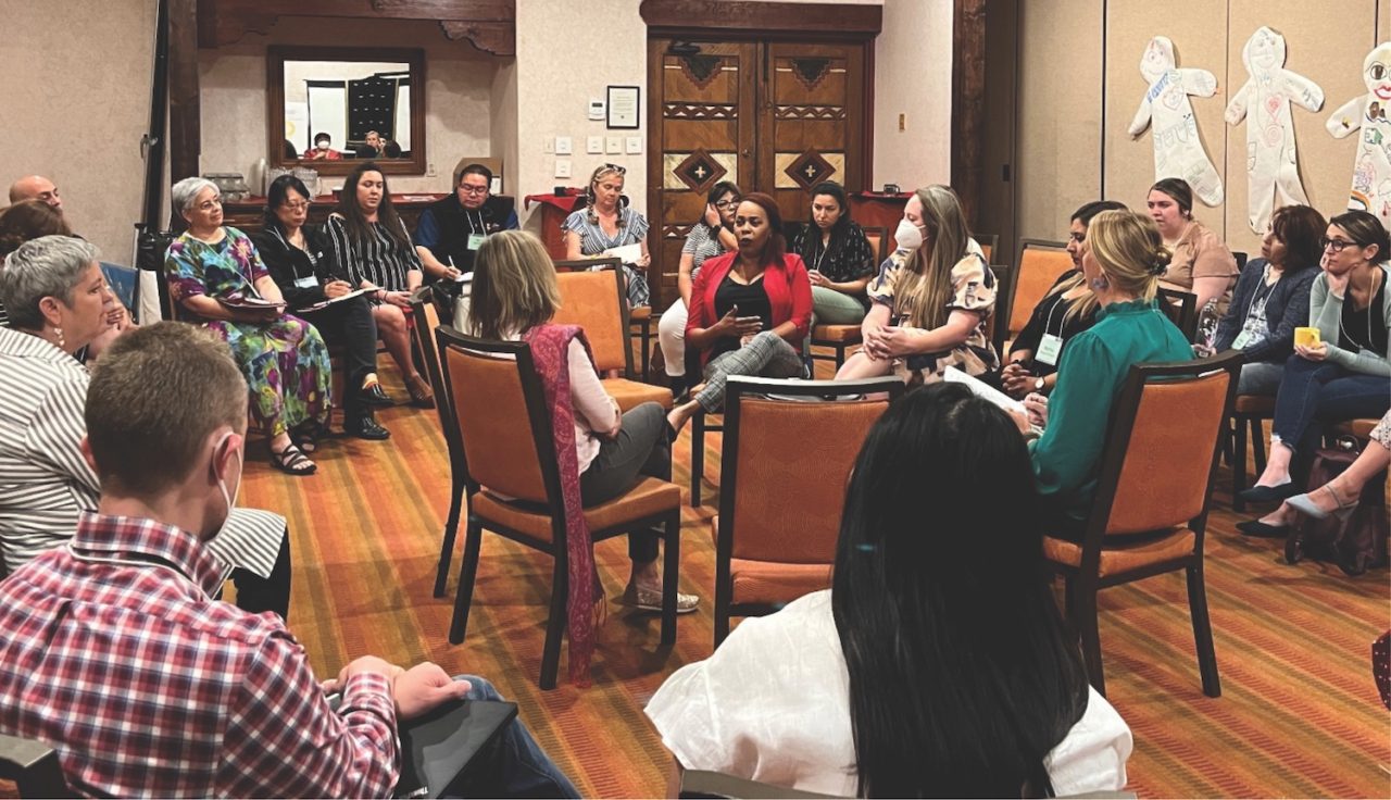 Group of people sit together in a circle in a conference room