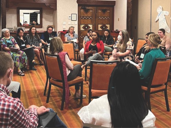 Group of people sit together in a circle in a conference room