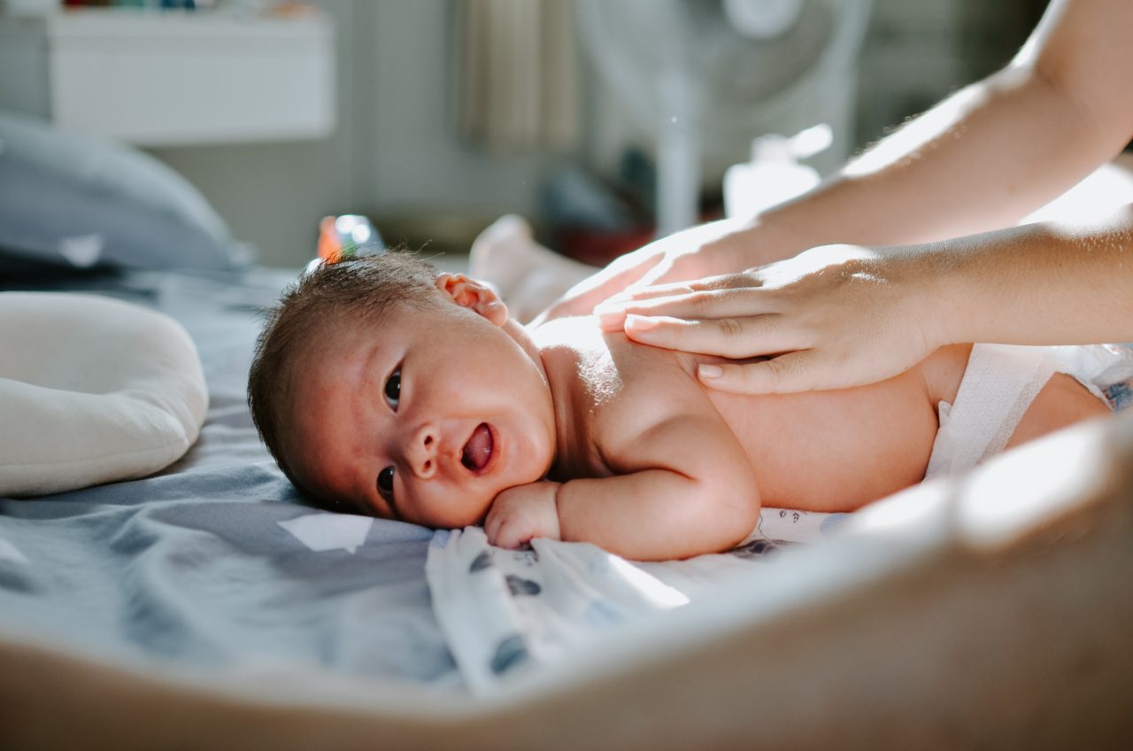 hands touch back of newborn