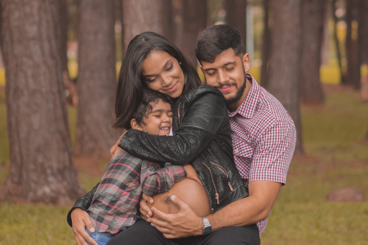 pregnant woman hugs son and husband