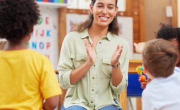 teacher clapping hands in front of four children in classroom