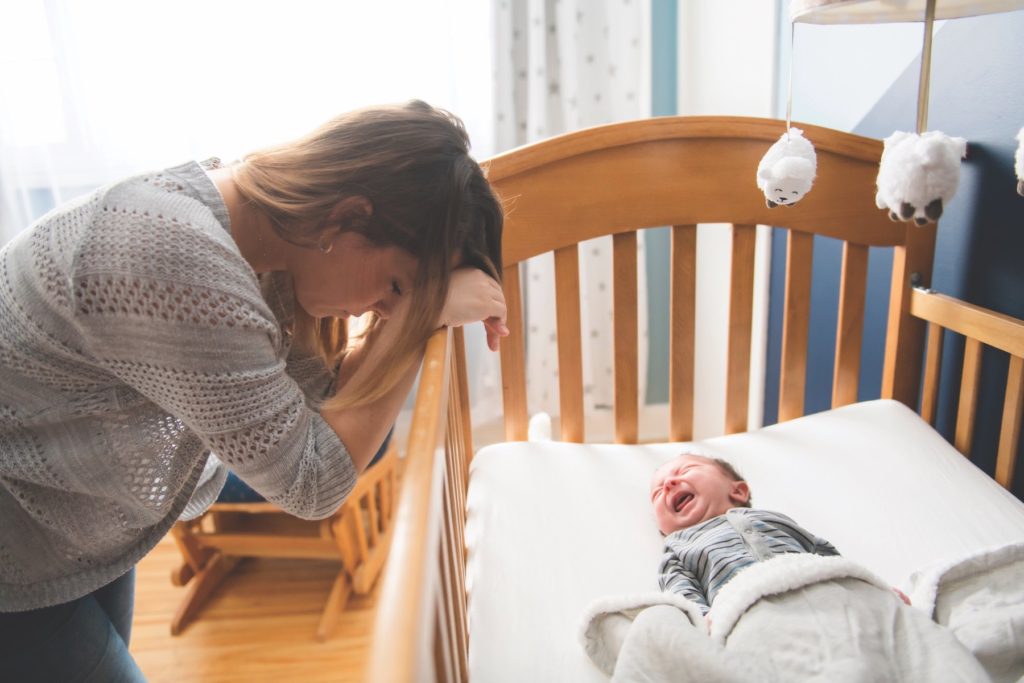 Tired Mother with Upset Baby Suffering with Post Natal Depression.