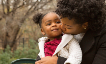 A mother kissing her toddler on the cheek, showing a secure attachment relationship.