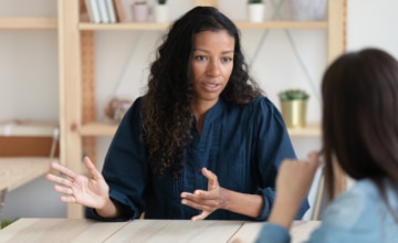 Photo of a Black woman talking to a colleague at work.