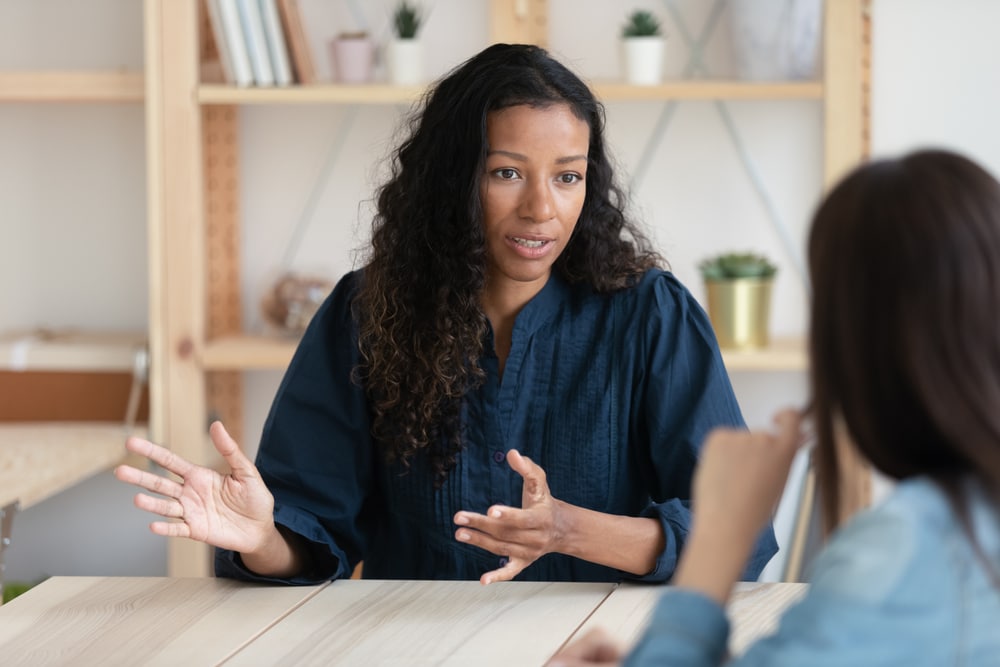 Photo of a Black woman talking to a colleague at work.