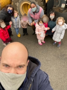 Preschool students, teachers, and adult male in foreground wearing masks.