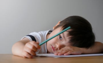 Sad child with head down at a desk