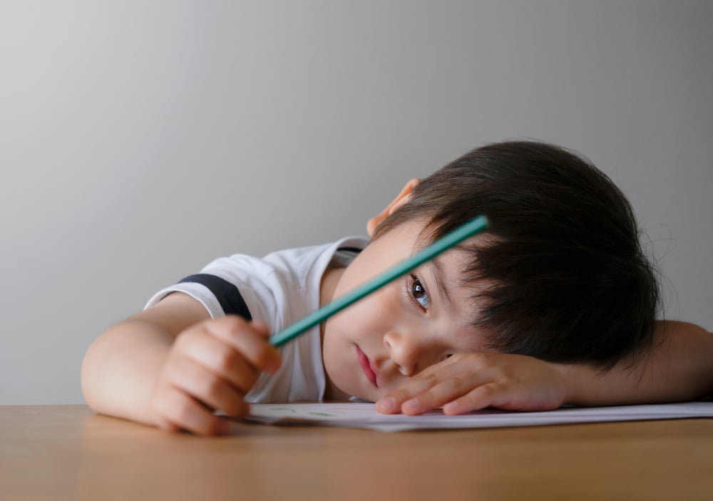 Sad child with head down at a desk