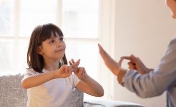 Girl signing to an adult, whose hands we see.