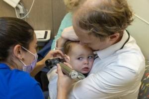 A father and toddler while the pediatrician checks his ears