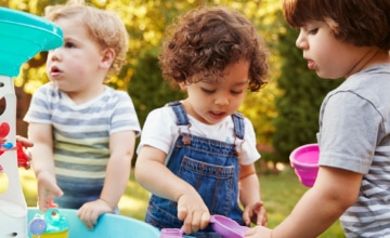 Toddlers playing together outside at a water table