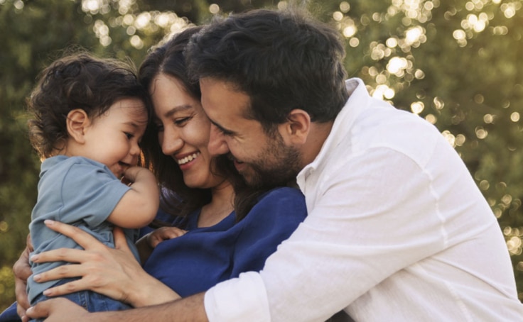 Parents holding a toddler and smiling