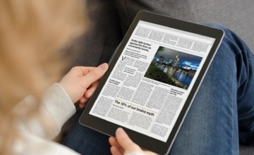 A person looking down at a tablet reading news articles