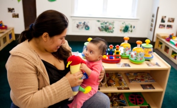 A child care provider sits with an infant on her lap