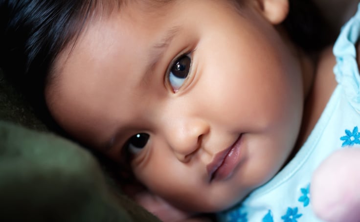 Close up photo of an infant's face looking into her eyes