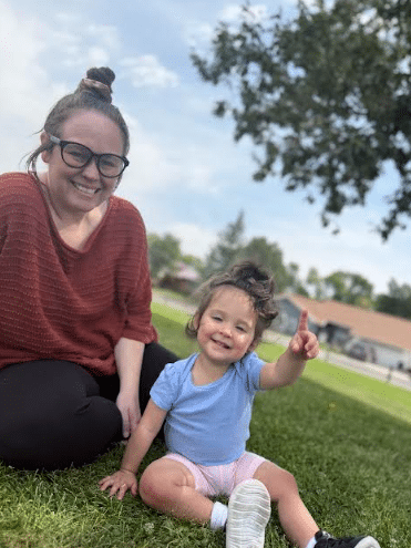Bry's and he daughter smiling sitting on the grass