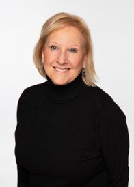 a smiling woman with blonde should length hair wearing a black long sleeve turtleneck sweater