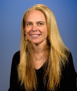 a smiling woman with long blonde hair wearing a black v-neck sweater