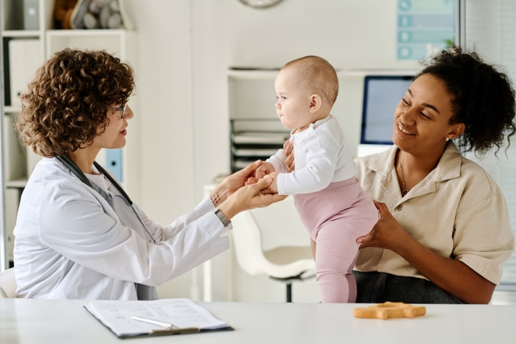 Female medical provider and female caregiver holding a baby in a medical office