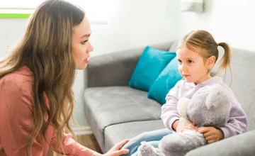 a woman in a desert orange shirt converses with a female toddler