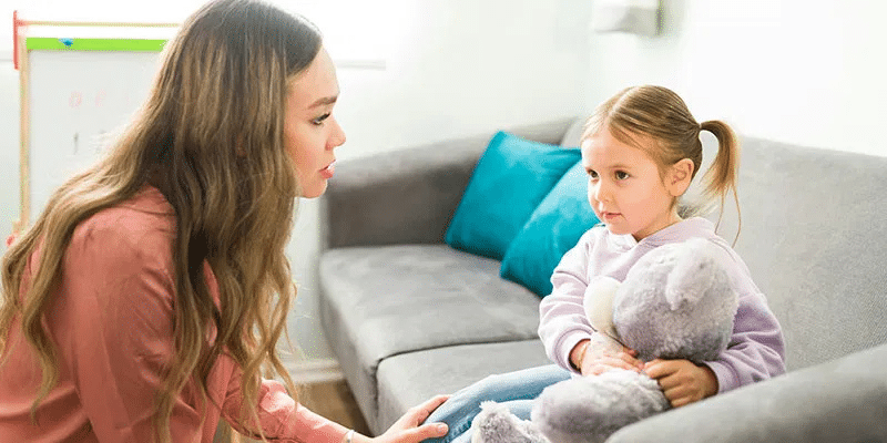 a woman in a desert orange shirt converses with a female toddler