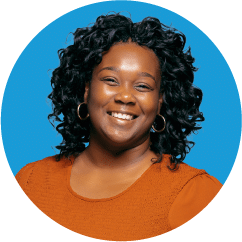 a smiling woman with shoulder-length black curly hair wearing an orange blouse