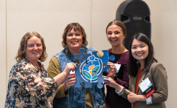 a group of smiling women hold a large puzzle piece