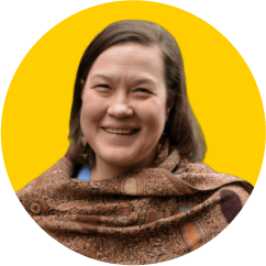 a smiling woman with long dark hair wearing a brown shawl
