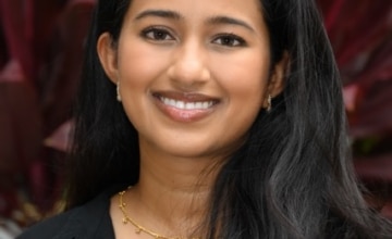 a smiling woman with long black hair wearing a black button up shirt