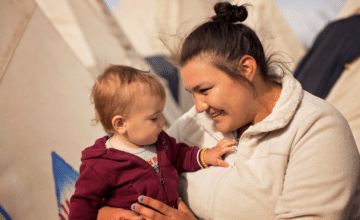 a smiling woman holds an infant