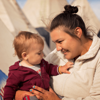 a smiling woman holds an infant
