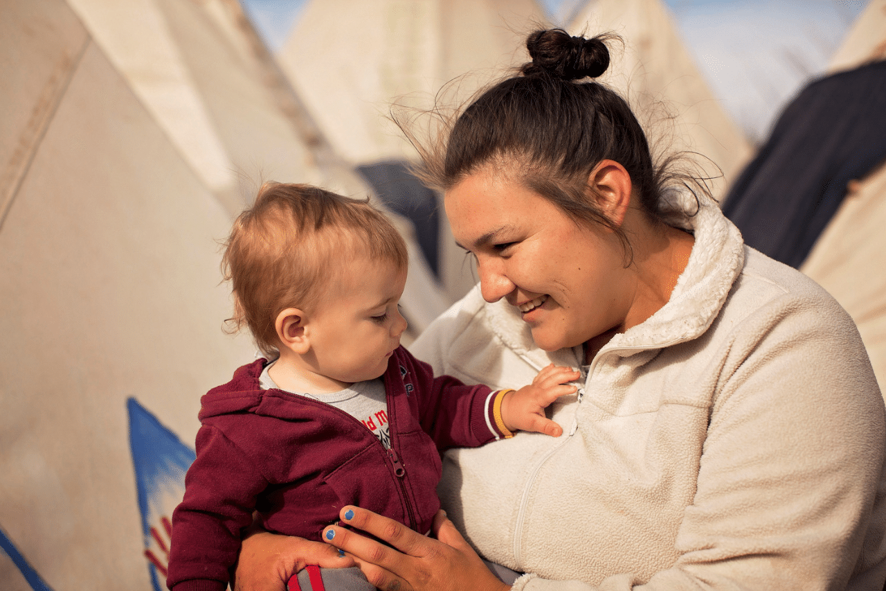 a smiling woman holds an infant