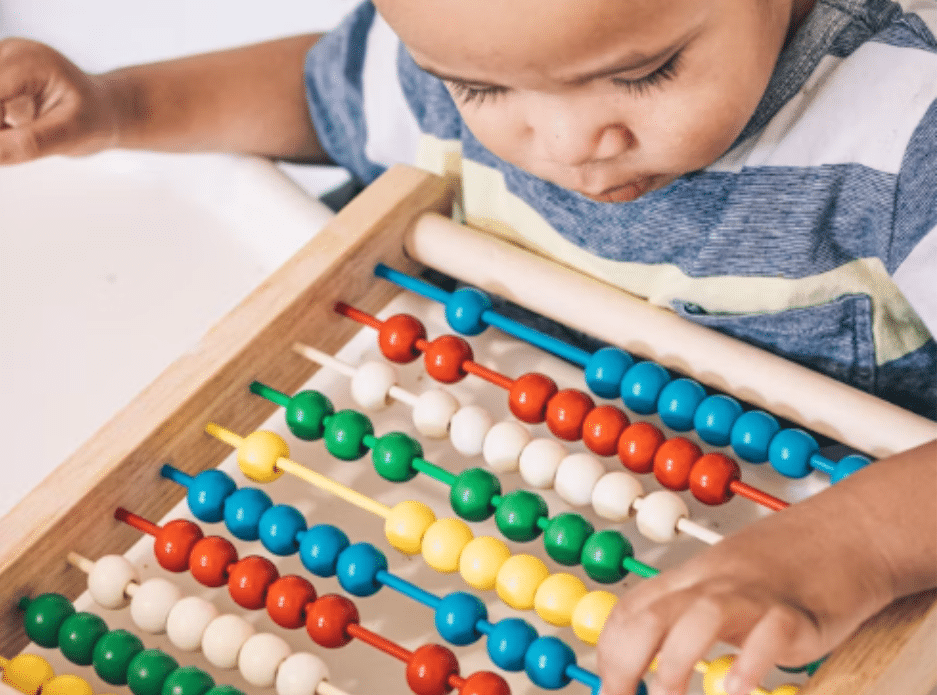 a toddler playing with colored balls on a rail