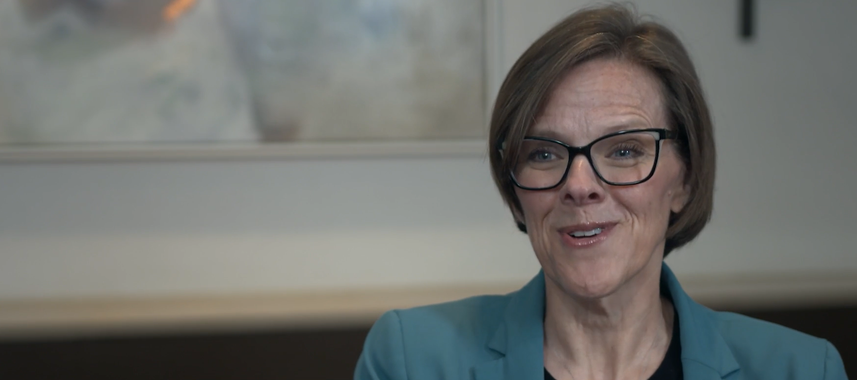 woman with short hair and glasses smiling at camera
