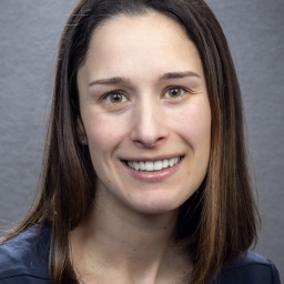 a smiling woman with shoulder-length brown hair wearing a navy crew neck shirt
