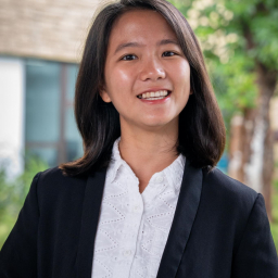 a smiling woman with long dark hair wearing a white button up blouse with navy blazer