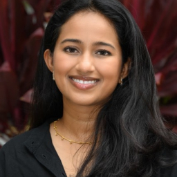 a smiling woman with long black hair wearing a black button up shirt