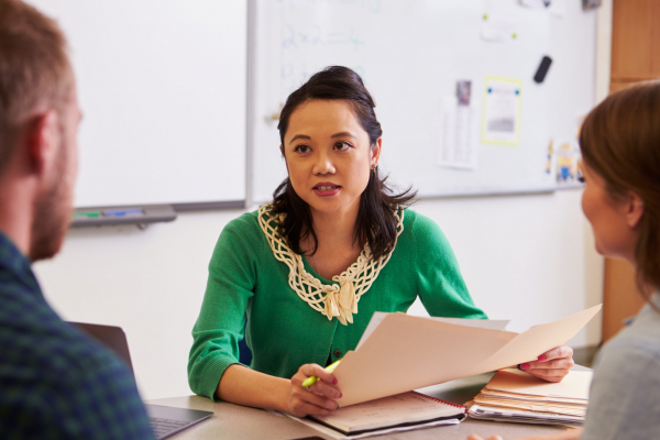 Teacher,At,Desk,Talking,To,Adult,Education,Students